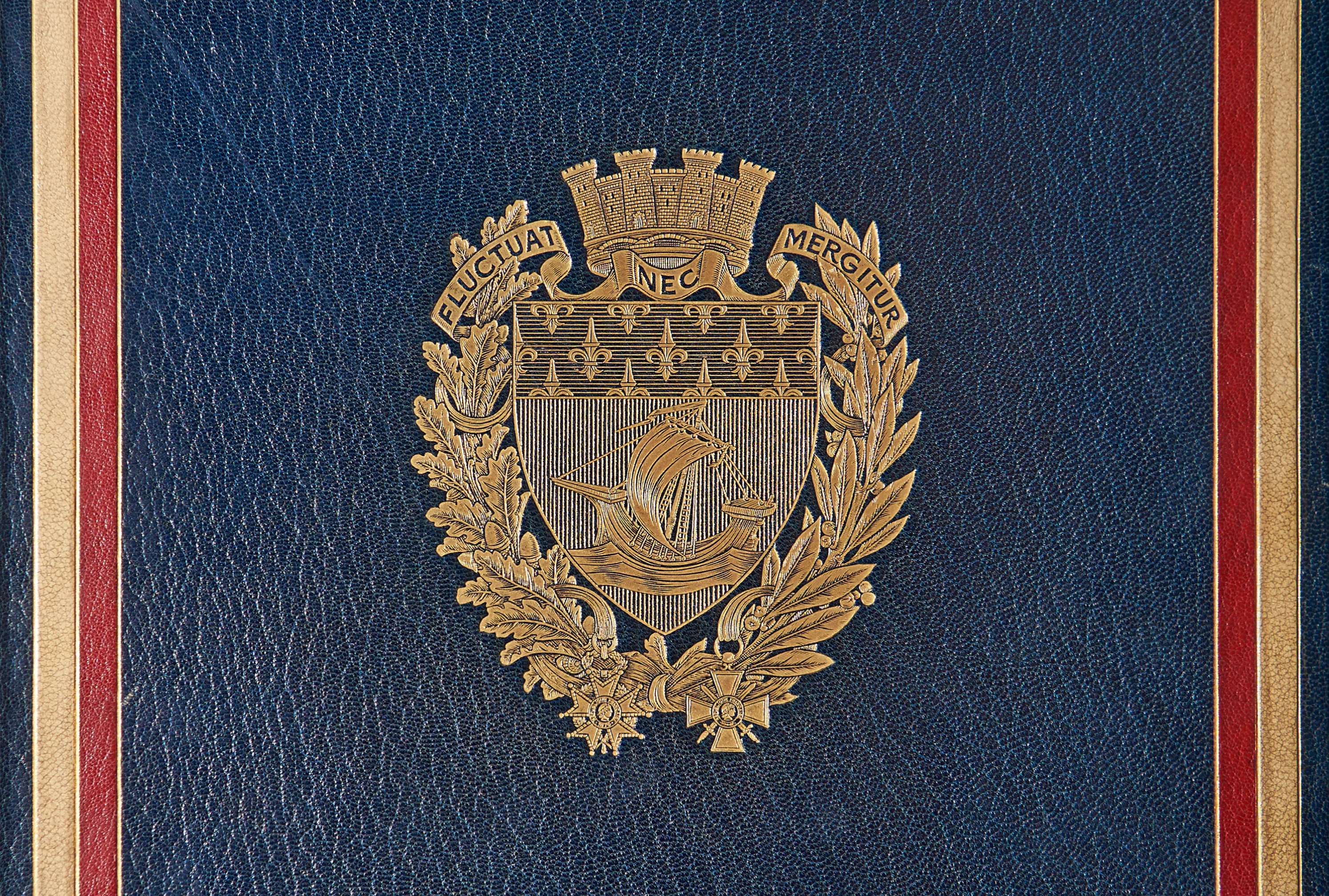 La nef,  blason de Paris, entourée de deux branches de chêne (puissance) et de laurier (victoire) auxquelles sont accrochées la Croix de la Légion d’honneur et la Croix de Guerre